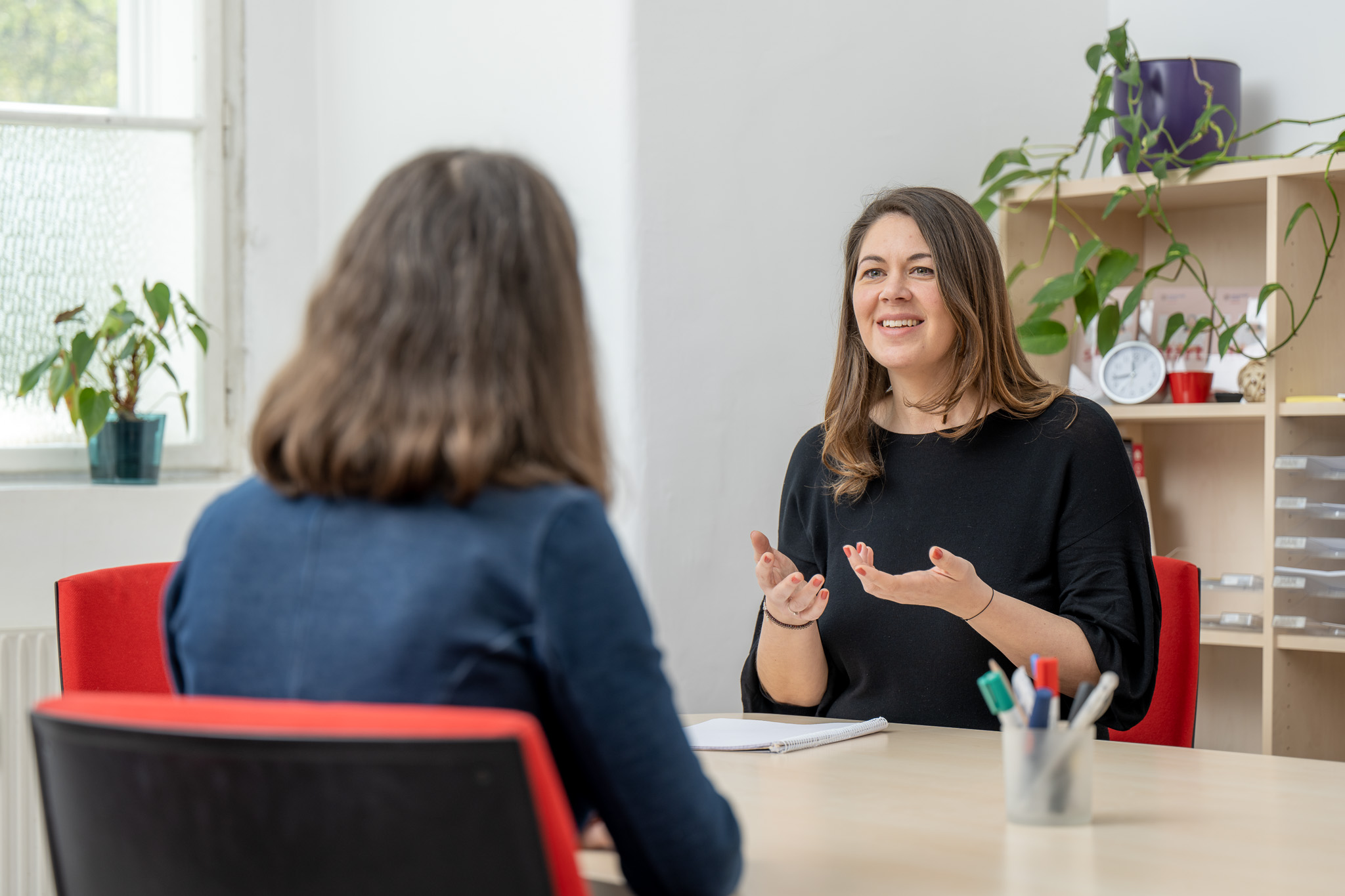 Two people sitting oppsite each other talking, staging a coaching session
